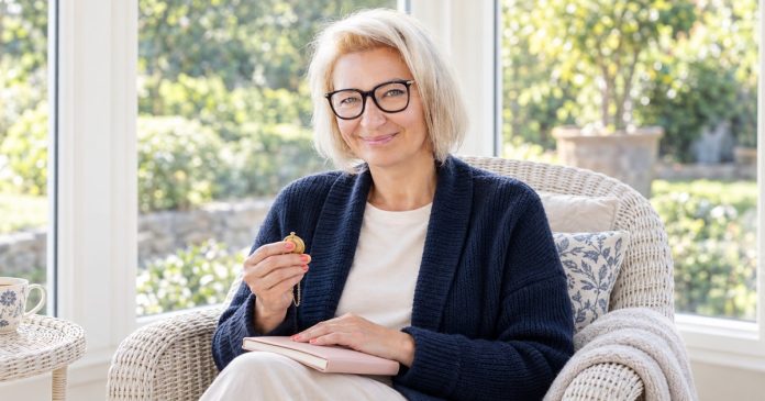 mediumship-grief-boundaries-distinct-model-20261014 Woman taking a quiet reflective pause with a keepsake and tea between mediumship appointments.